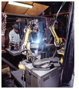 Robot cell with a welder in the background.
