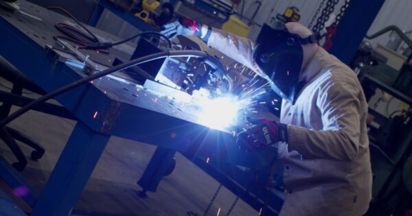 Bryan with Advanced Welding Solutions in an industrial setting completing a weld.